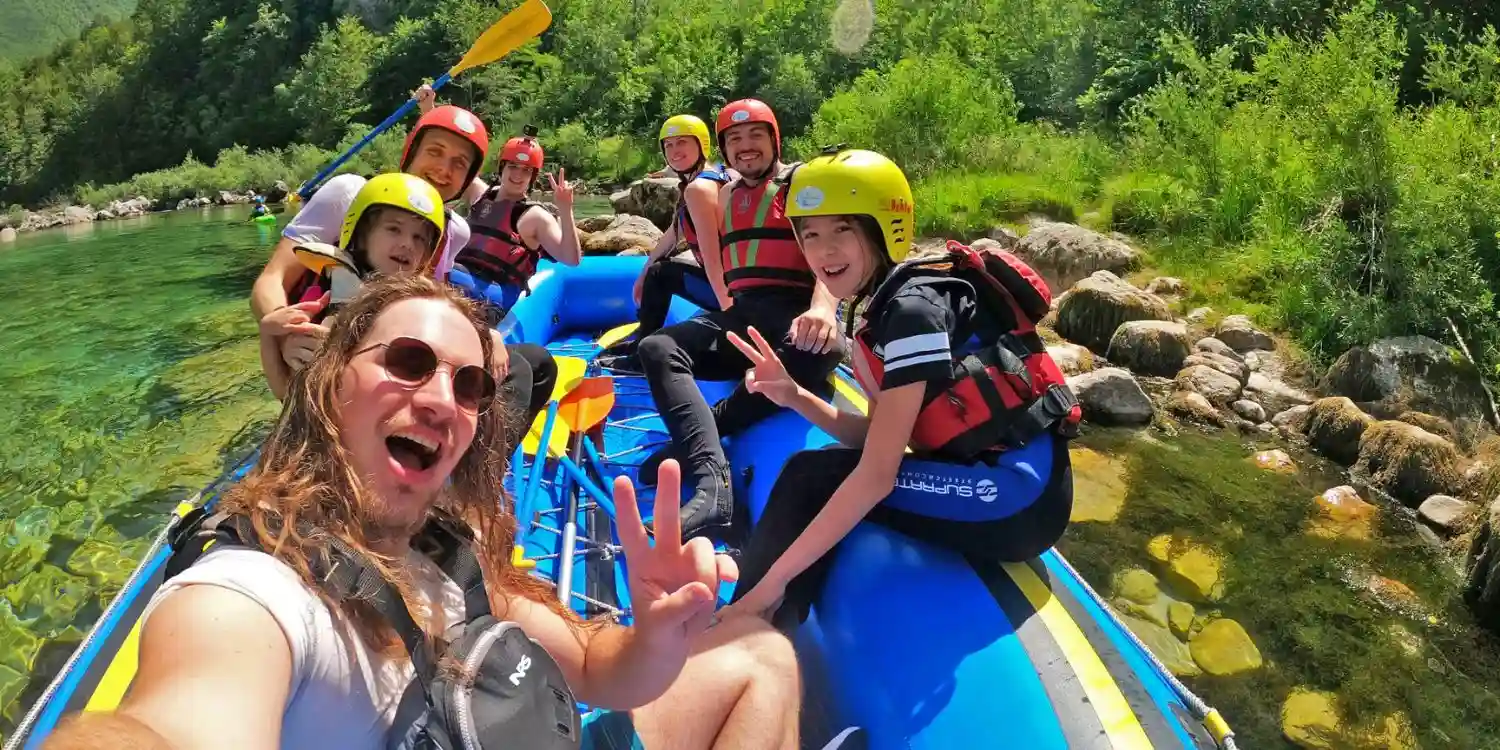 Happy group of beginners on a rafting boat navigating the emerald Soča river in Bovec
