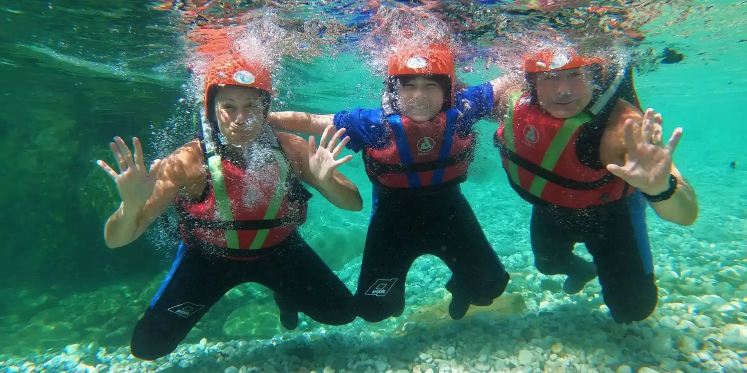 A happy family enjoying a unique underwater moment in the crystal clear Soča River during a private rafting tour with Bovec Rafting Team.