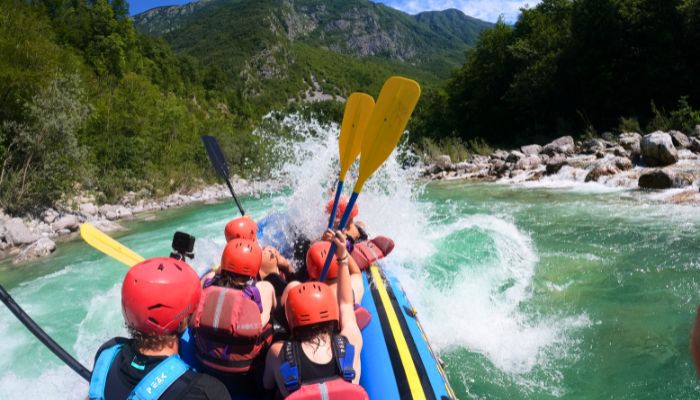 A team building group in full rafting gear navigating the whitewater rapids of the Soča River in the heart of the Triglav National Park near Bovec.