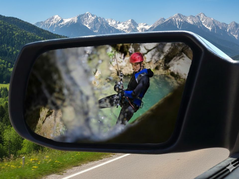 Canyoning guest rappelling in a mirror reflection with Julian Alps and road to Trenta in the background