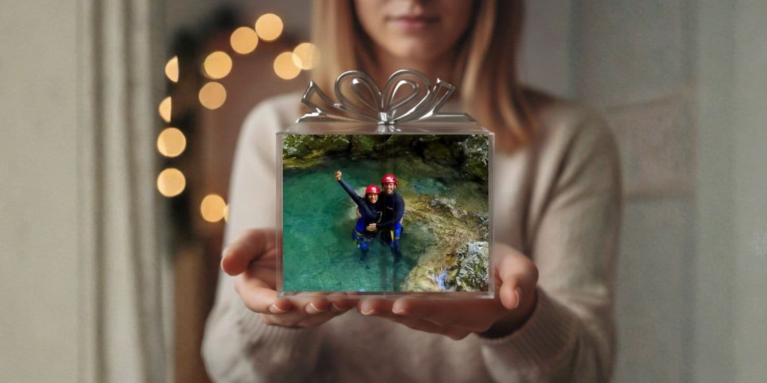 Female hands holding a glass gift box with a couple enjoying canyoning adventure in Bovec, Soča Valley.