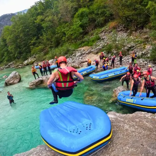 An adventurous man sliding down an overturned raft into the river like a water slide during a break.