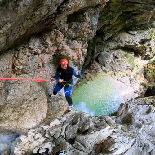 A guest safely rappelling down a waterfall using a rope during a private canyoning trip in Fratarica.