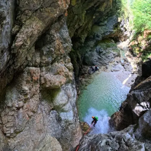 Close-up of a guest navigating a waterfall descent on a rope during a private canyoning tour.