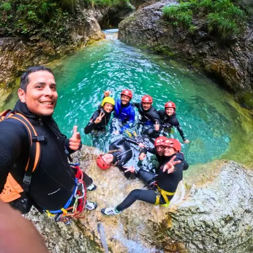 Professional guide Sergio taking a fun GoPro selfie with a group of smiling guests in a canyon pool.