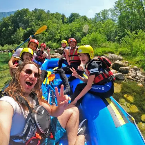 A happy selfie taken by a professional Bovec Rafting Team guide with a group of smiling guests on a raft.