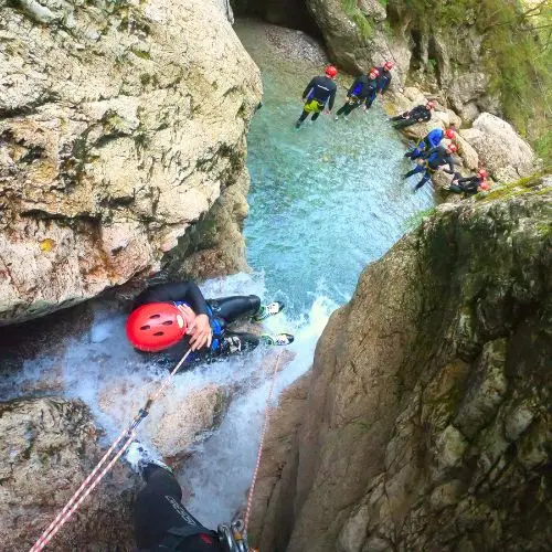 A guest sliding down a smooth natural rock formation into a waterfall in the Sušec stream.