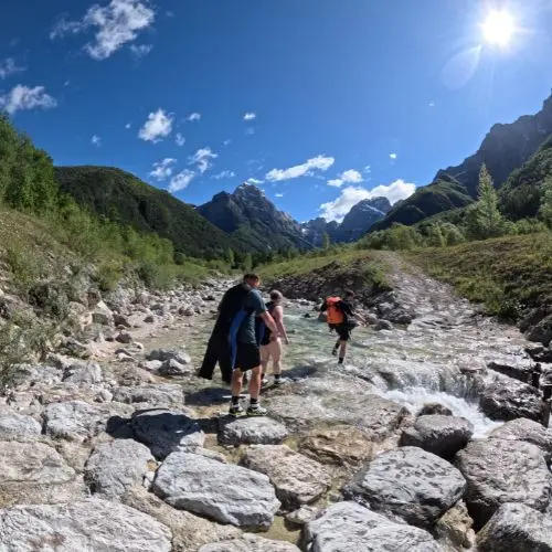 Guests hiking through the forest of Triglav National Park carrying canyoning gear towards Fratarica canyon.