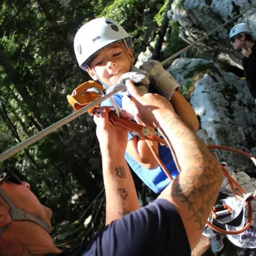 A professional guide explaining safety procedures and braking techniques to a young boy before the zipline descent.